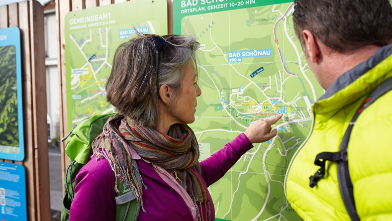 Two people look at a hiking map of Bad Schönau.