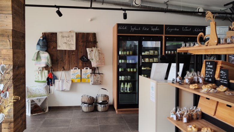 Innenansicht eines Dorfladens mit Regalen voller Produkte und Dekorationen.