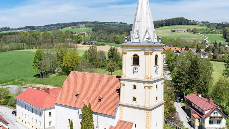 Luftaufnahme der Wehrkirche Krumbach in einer ländlichen Umgebung mit grünen Feldern und blauem Himmel.