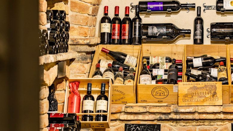 Weinflaschen in einem rustikalen Weinkeller mit Backsteinwänden.