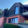 Modern house with wooden shingles and large windows.