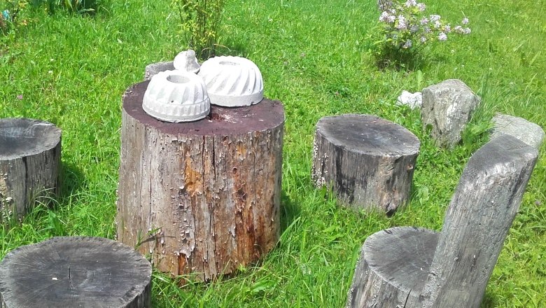 Garten mit Baumst&uuml;mpfen als Sitzgelegenheiten und Tisch, dekoriert mit Betonformen.