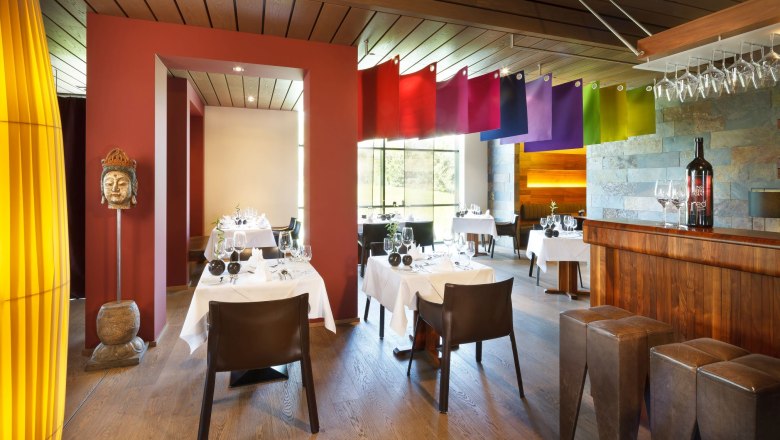 Elegantes Restaurant mit gedeckten Tischen, bunten Dekorationen und einer Buddha-Statue.