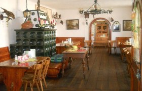 Innenansicht eines traditionellen österreichischen Heurigen mit Holzmöbeln und Kachelofen.