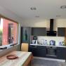 Modern kitchen with gray cabinets, stove, sink and table with colorful tablecloth.