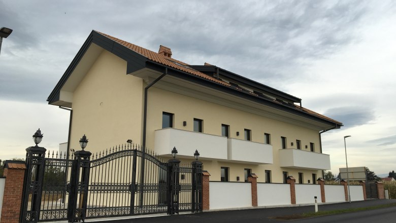 Außenansicht eines modernen Gebäudes mit Ziegeldach und schmiedeeisernem Tor.