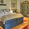 Elegant bedroom with double bed, antique wardrobe and red carpets.