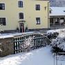 Snow-covered yellow building with green fence in the foreground.
