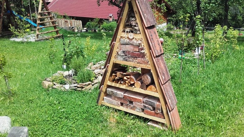 Ein Insektenhotel in einem Garten mit Rasen und B&auml;umen.