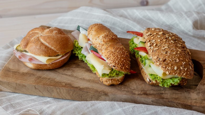 Three sandwiches on a wooden board.