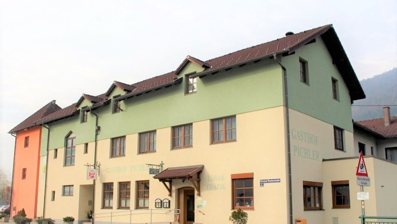 Unser Gasthof, © Peter Pichler Ein zweistöckiges Gebäude mit der Aufschrift 'Gasthof Pichler', gelb und grün gestrichen, mit braunem Dach und mehreren Fenstern.