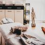 Ein Spa-Raum mit Massageliege, Handtüchern, Buddha-Statue und Kerzen.
