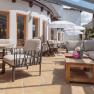 Moderne Terrasse mit bequemen Sitzmöbeln, Holztischen und Sonnenschirmen.
