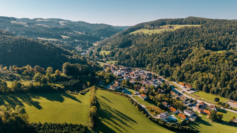 Luftaufnahme von Edlitz mit Wehrkirche, umgeben von grünen Hügeln und Wäldern.