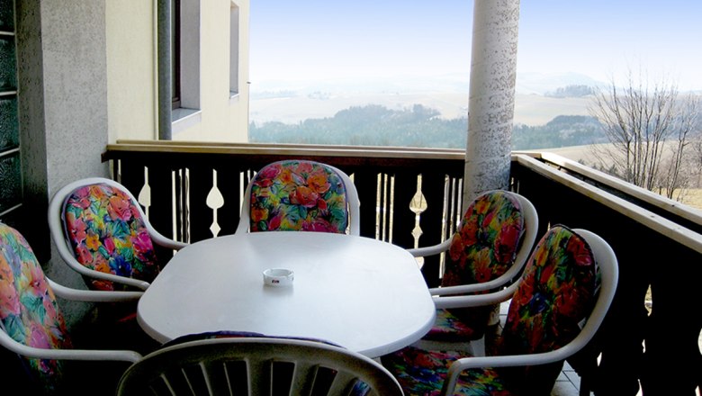 Balkon mit Tisch und bunten St&uuml;hlen, Aussicht auf Landschaft.