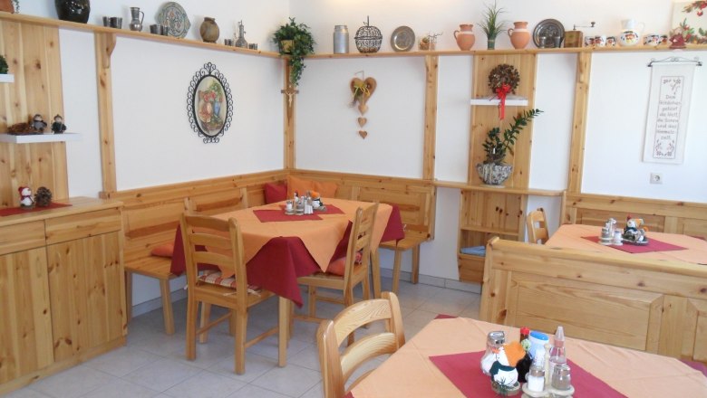 Gemütlicher Frühstücksraum mit Holzmöbeln und Dekorationen an den Wänden.