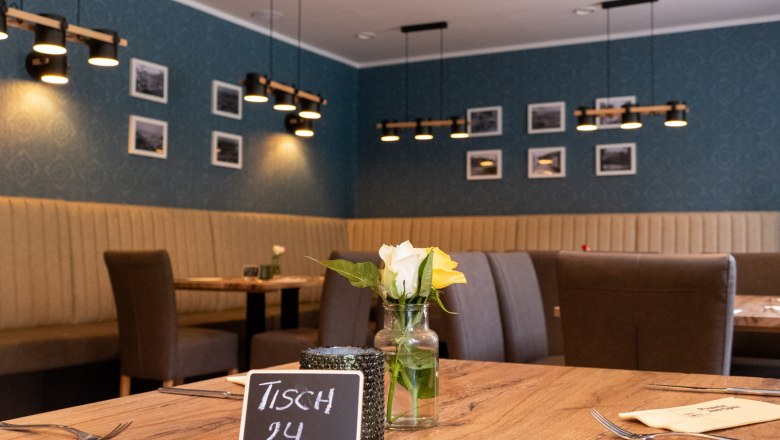 Interior view of a restaurant with wooden table, flowers and modern lighting.