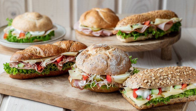 Verschiedene belegte Brötchen auf Holzbrett arrangiert.