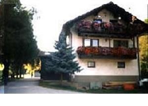 Ein traditionelles Haus mit Blumenkästen auf dem Balkon, umgeben von Bäumen.