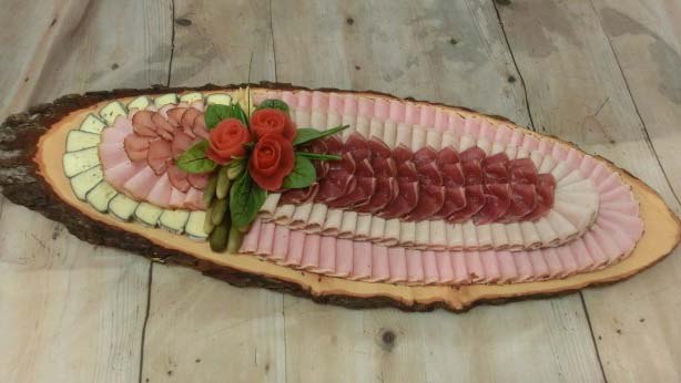 Kunstvoll angerichtete Platte mit Wurst und Käse auf einem Holzbrett.