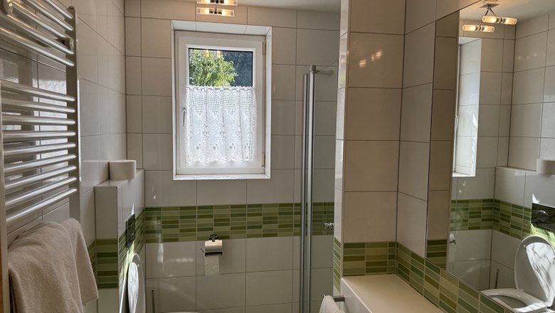 Modernes Badezimmer mit grünen Fliesen, Dusche, WC und Waschbecken.