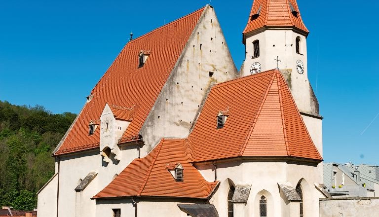 Wehrkirche Edlitz mit vielen Seitenbereichen, roten Ziegeld&auml;chern, einem spitzen Turm und blauem Himmel.