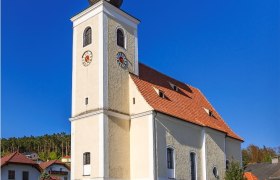 Pfarrkirche Hollenthon mit Zwiebelturm und blauen Himmel.