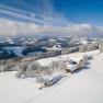 Snowy landscape with farm and hills in the background.