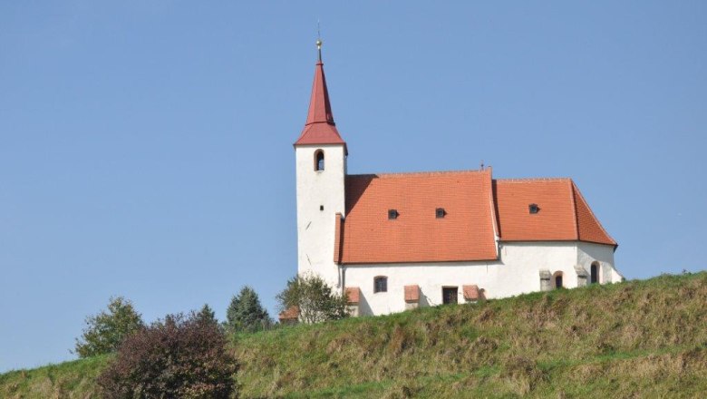 Pfarrkirche Ofenbach auf einem H&uuml;gel mit blauem Himmel im Hintergrund.
