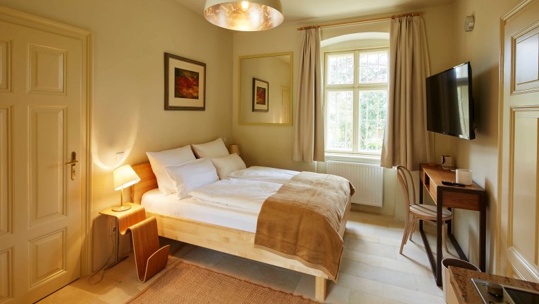 Gem&uuml;tliches Schlafzimmer mit Doppelbett, Schreibtisch und gro&szlig;em Fenster.