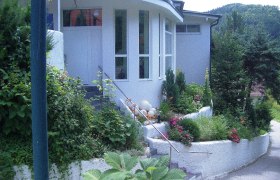 Eingang eines modernen Gebäudes mit Garten und Treppe.