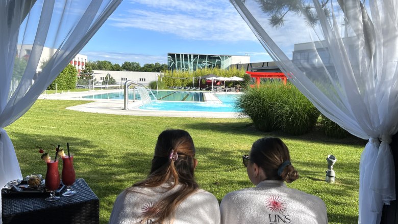 zwei damen liegen auf den bauch uns sehen auf das blaue Wasser des Schwimmbeckens