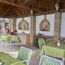 Covered terrace with green tablecloths, white chairs and rustic decorations.