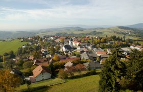 Luftaufnahme von Hochneukirchen-Gschaidt mit Häusern, Kirche und grüner Landschaft.