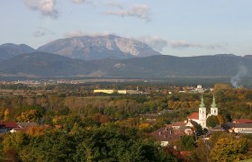 Panorama von Schwarzau am Steinfeld mit Kirche und Bergen im Hintergrund.