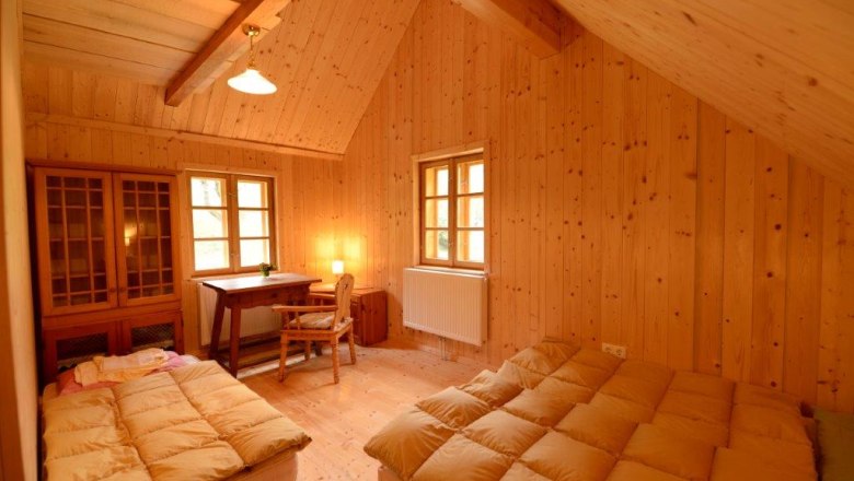 Holzvert&auml;feltes Zimmer mit zwei Betten, Schreibtisch und Stuhl.