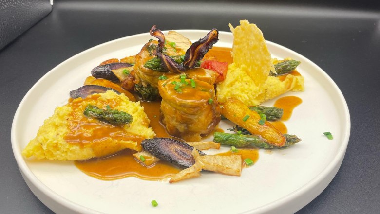 Gourmetgericht auf wei&szlig;em Teller mit Fleisch, Gem&uuml;se und Sauce.