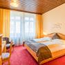 Gemütliches Hotelzimmer mit Doppelbett, Holzmöbeln und rotem Teppich.
