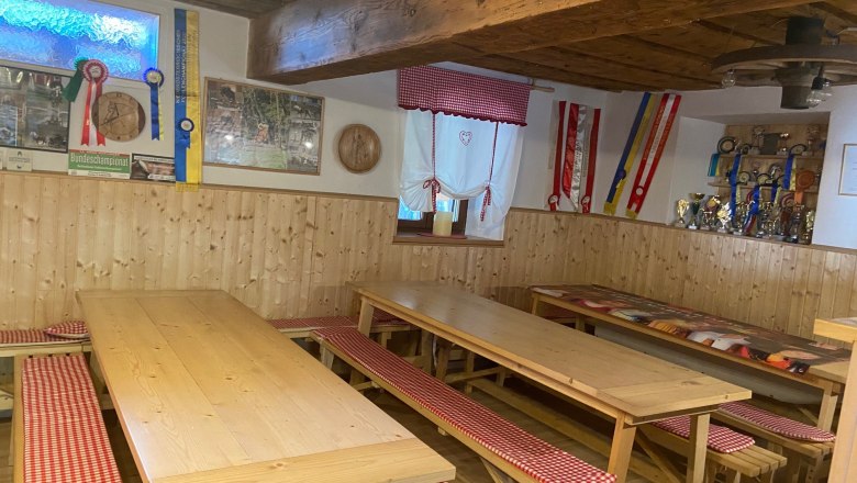 Gemütlicher Gemeinschaftsraum mit Holztischen, Bänken und Dekorationen an den Wänden.