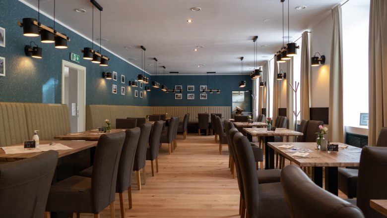 Interior view of an elegant restaurant with wooden floor, gray chairs and blue walls.
