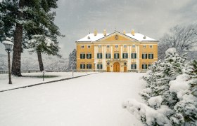 Frohsdorf kast&eacute;lya sok ablak&aacute;val &eacute;s s&aacute;rga homlokzat&aacute;val, amelyet t&eacute;len h&oacute; bor&iacute;t.
