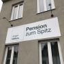 Facade of a building with a sign for the Pension zum Spitz.