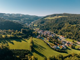 Luftaufnahme von Edlitz mit Wehrkirche und umliegender Landschaft.