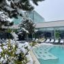 Außenbereich der Therme Linsberg Asia mit schneebedeckten Bäumen und Liegestühlen, neben einem Pool.