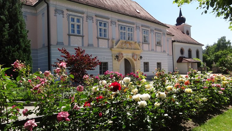 Barockgebäude mit Rosengarten im Vordergrund.