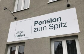 Facade of a building with a sign for the Pension zum Spitz.