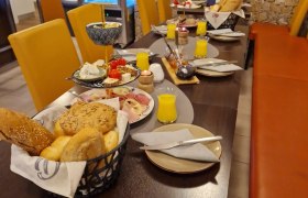 Frühstückstisch mit Brötchen, Aufschnitt und Orangensaft in einem Café.