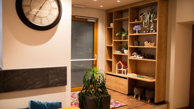 Innenansicht eines Bistros mit großer dekorativer Uhr, Regal und Kinderspielecke.