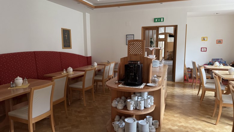 Innenansicht eines Frühstücksraums mit Holzmöbeln und Geschirr.