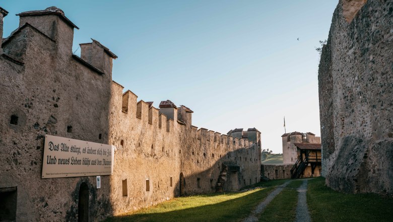Innengang der Burgruine Kirchschlag mit alten Steinmauern und einem Schild mit Inschrift.